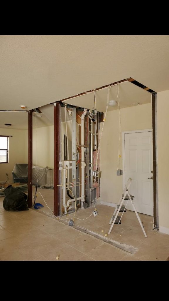 Electrical and plumbing rough-in exposed during a wall removal by Onel Construction in South Florida