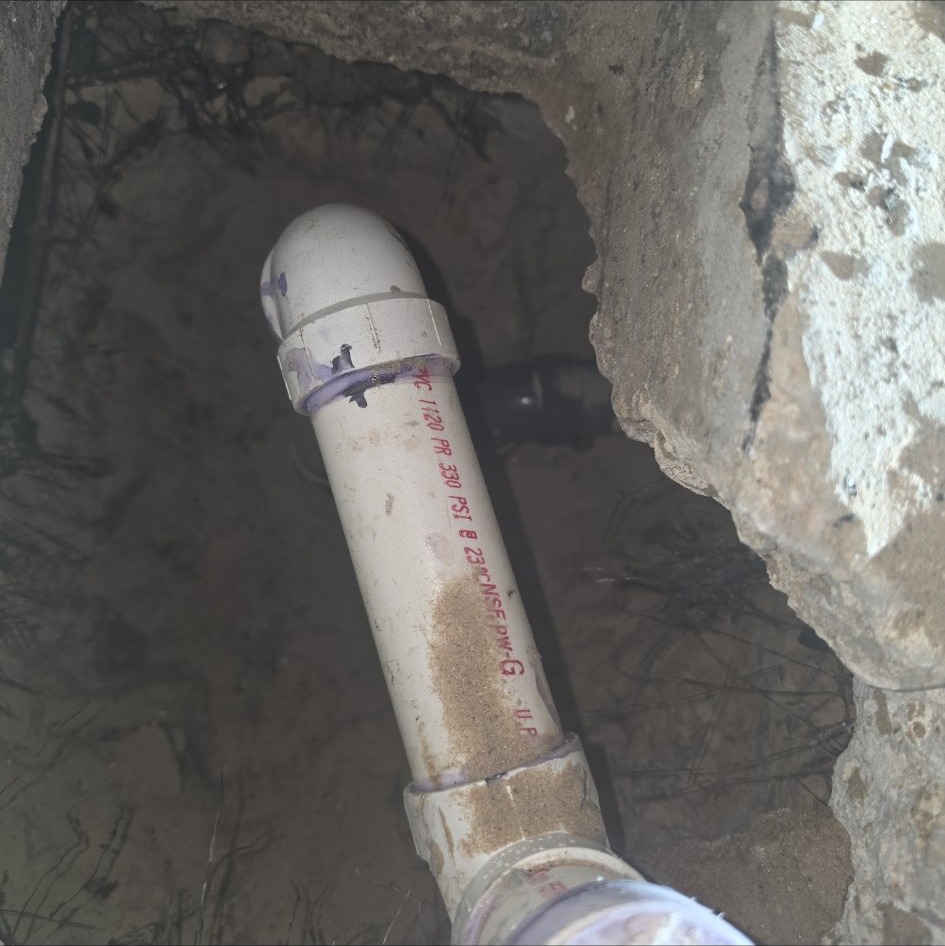 Close-up of new under-slab PVC drain piping with purple primer on a bathroom remodel by Onel Construction in South Florida