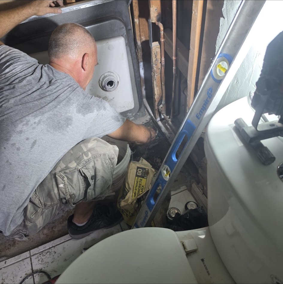 Plumber roughing in a shower drain during a bathroom remodel by Onel Construction in South Florida